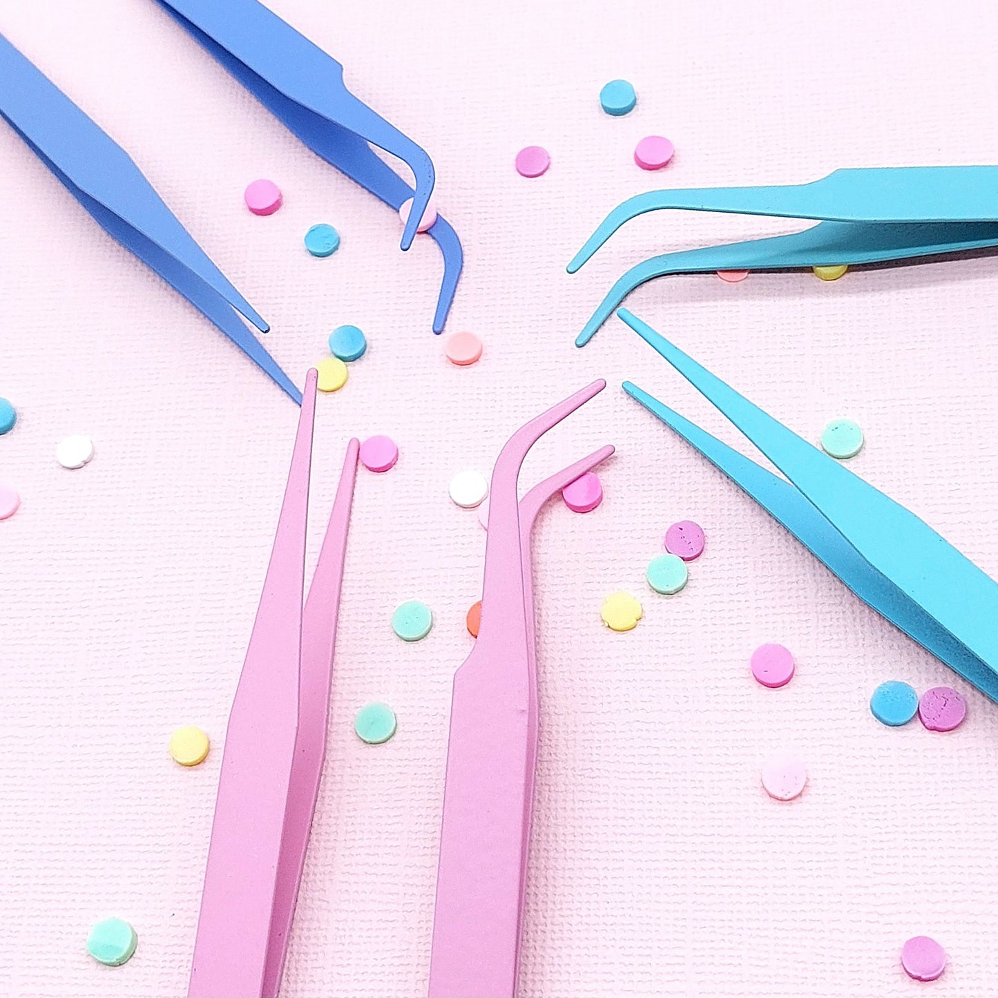 Colorful tweezers on a pink background with colorful dots