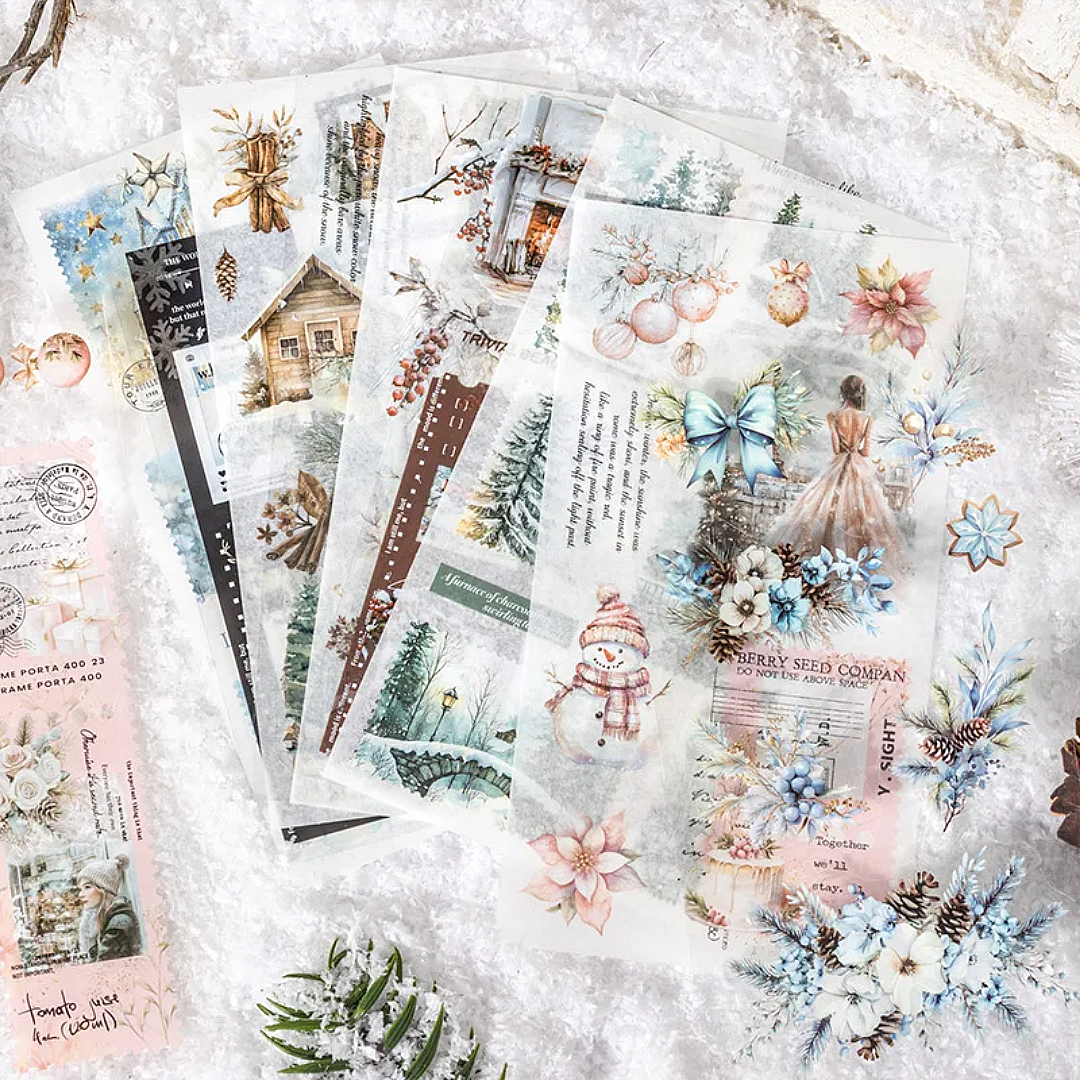 Collection of decorative washi paper and P.E.T sheets from inside the sticker book with winter-themed designs on a snowy surface.