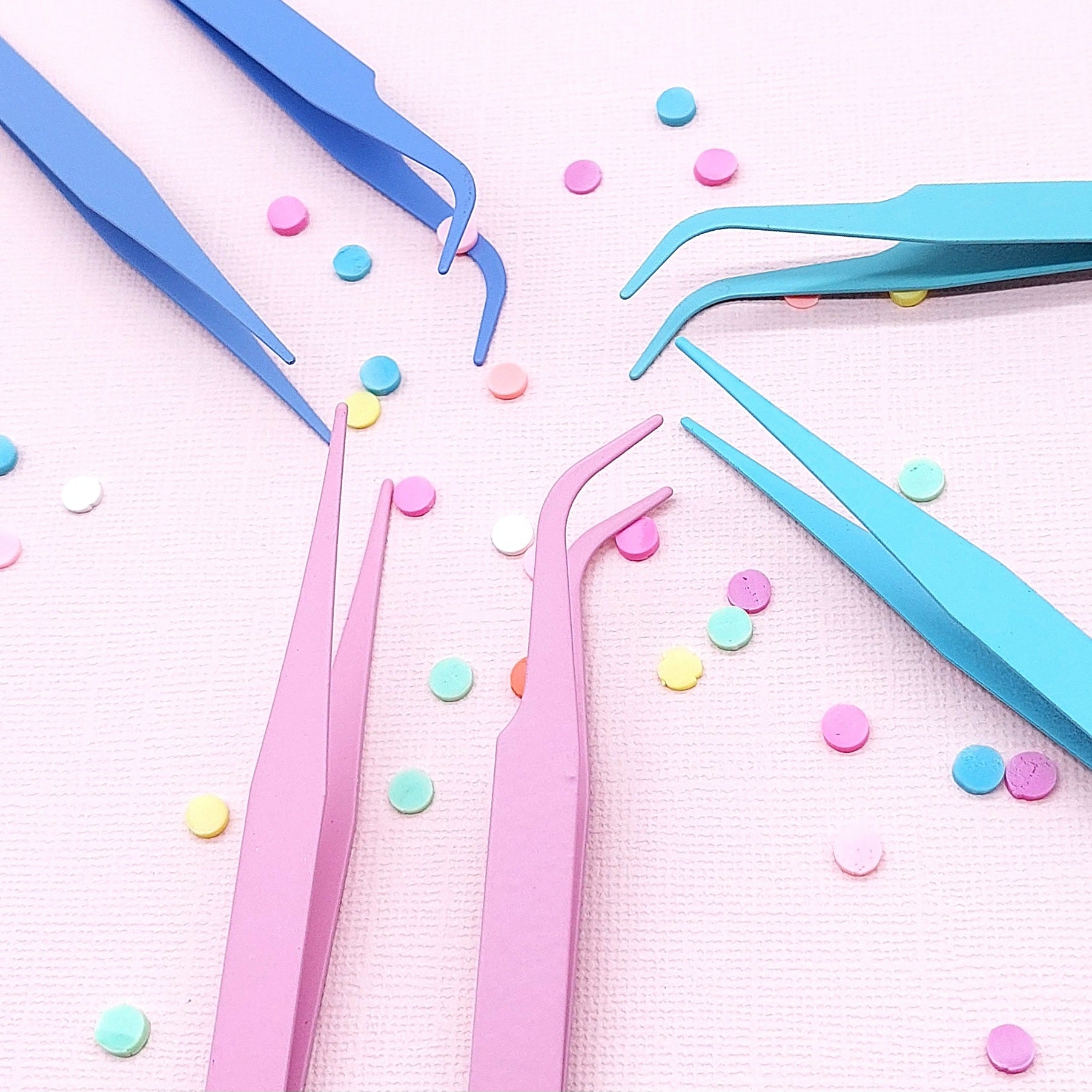 Colorful tweezers on a pink background with colorful dots