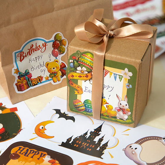Gift box with a gold ribbon and Easter-themed stickers on a table with Halloween-themed cards.