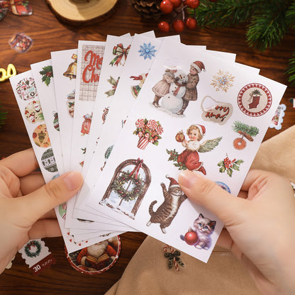 Set of Christmas-themed stickers held by hands on a wooden surface with decorative items.